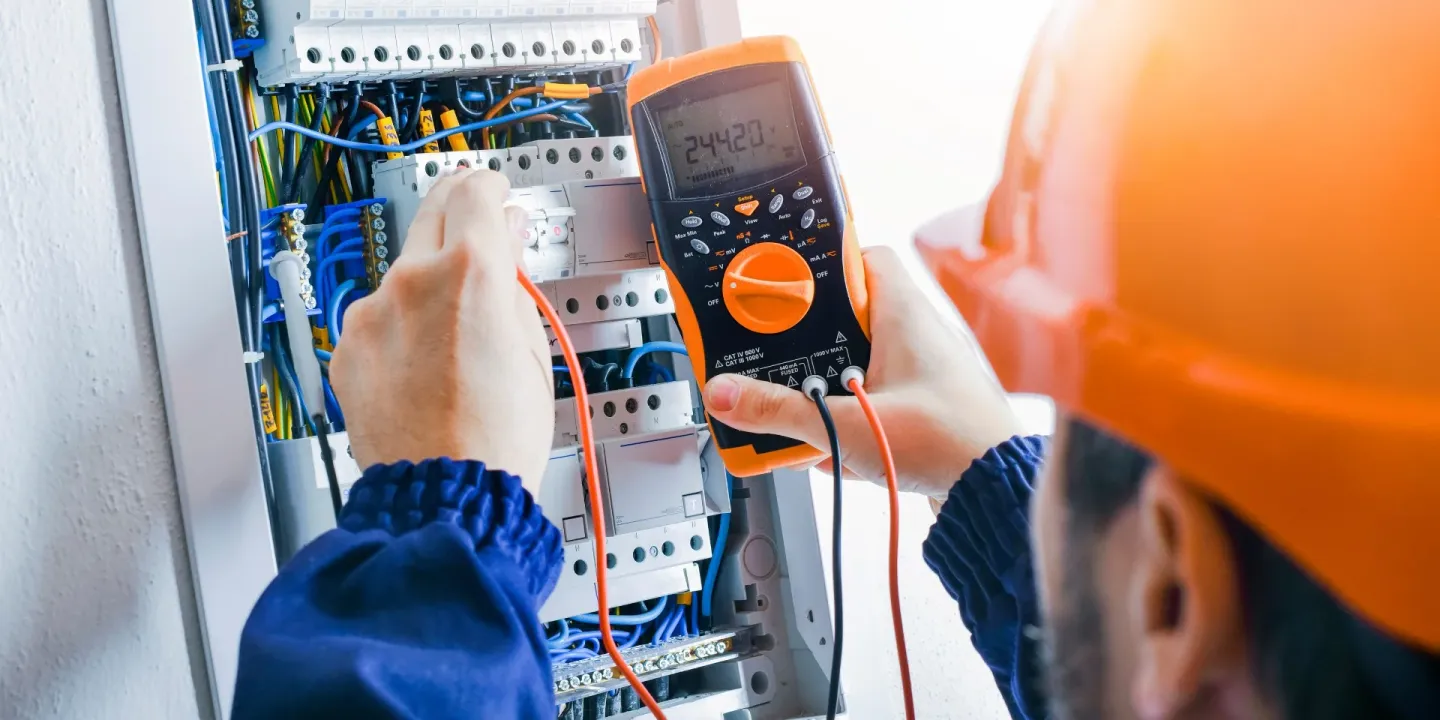 Elektriker mäter i en elcentral med multimeter